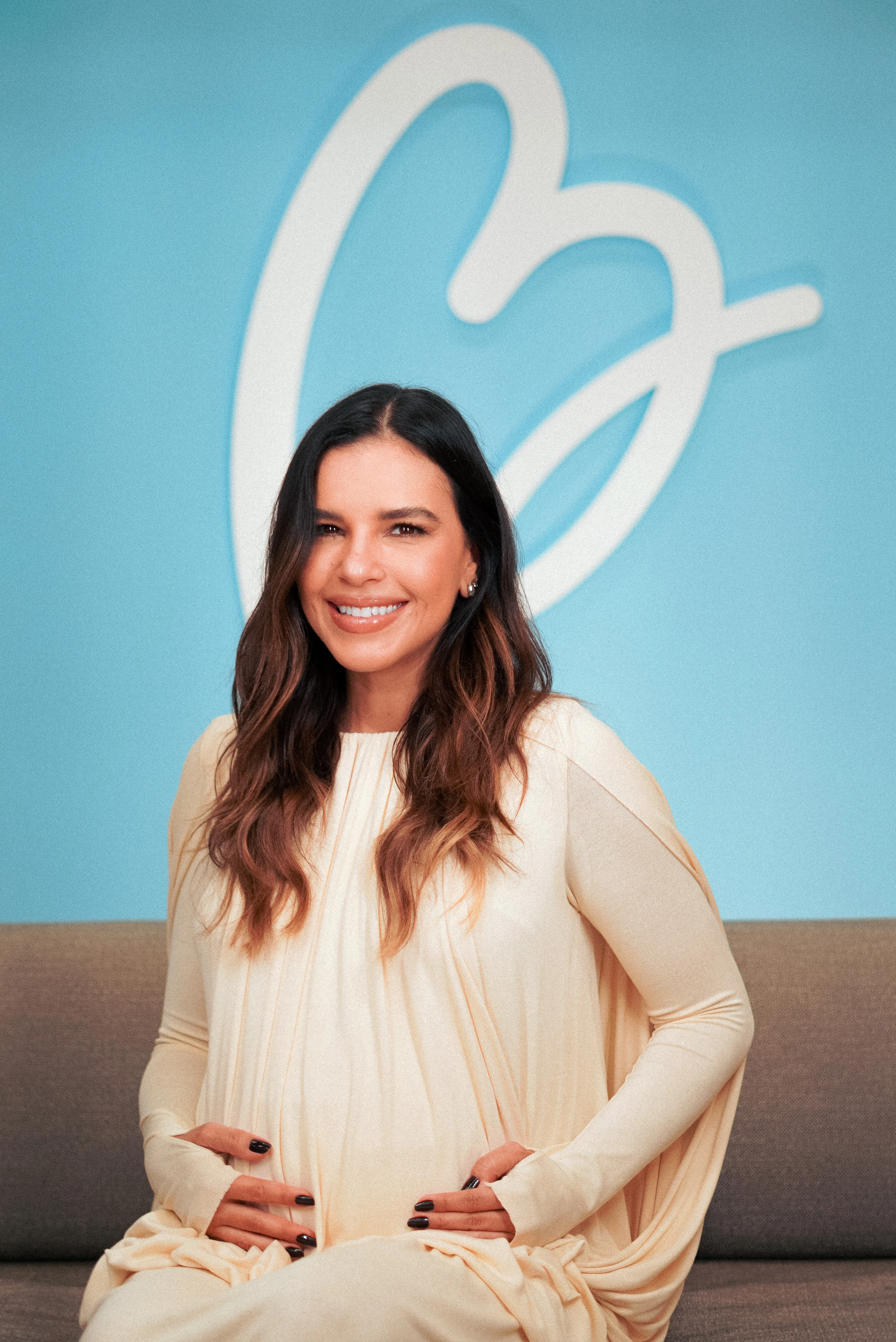 Mariana Rios grávida diante da identidade visual do Basta Sentir Maternidade